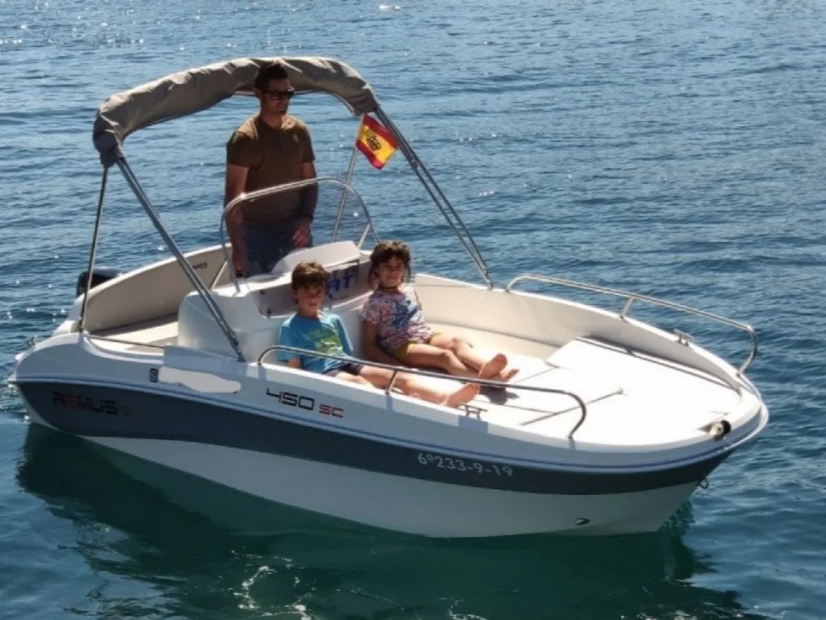 Family navigating a boat along the Costa Brava coast